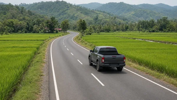 Foto pikap melaju di jalan panjang yang membelah sawah
