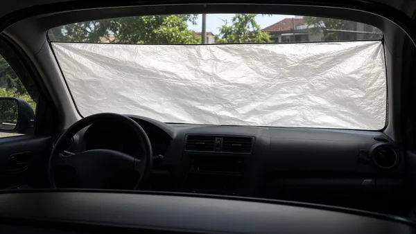 Foto dasbor sedan dengan pelindung matahari terpasang di kaca depan