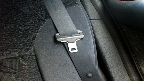 Foto pria memeriksa sabuk pengaman kursi baris kedua MPV keluarga dengan pintu terbuka