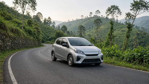 Foto city car melaju di jalan antarkota dengan latar perbukitan hijau