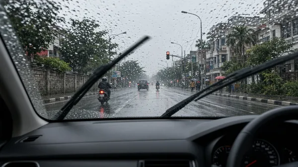 Foto hujan di kaca depan dengan wiper bergerak, terlihat dari dalam mobil