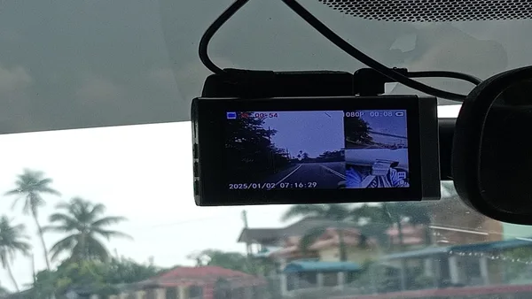 Foto dashcam terpasang di balik spion tengah dengan kabel dirapikan di sepanjang plafon dan pilar kaca